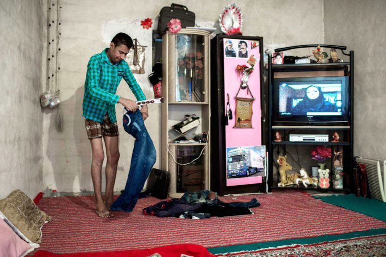 Ghaffar getting dressed in his home. Iran, November 2014.