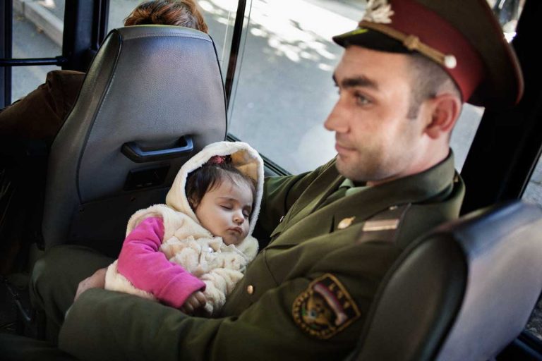 Stepanakert. A civil policeman on the bus with his daughter. Nagorno-Karabakh's Police has two branches: the civil one, wearing green and grey uniforms, and the military one, wearing dark uniforms.